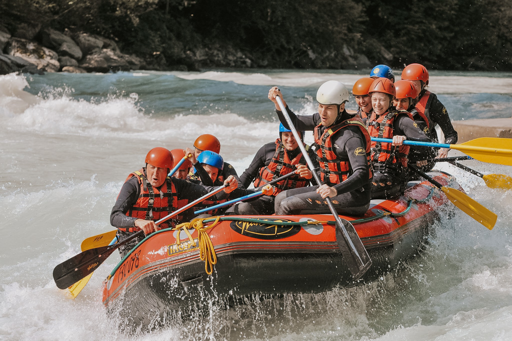eleven people ride a red raft with turbulent river water with helmets on on a white water rafting La Fortuna activity