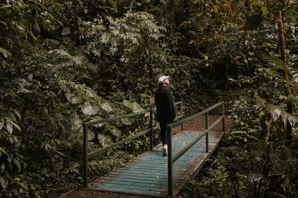 woman walking across small wooden bridge on one of the best things to do in Monteverde Costa Rica