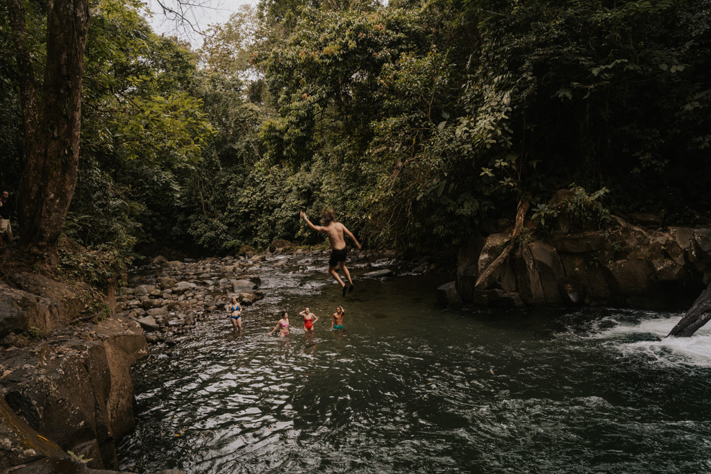a man jumping from the El Salto rope swing into a lagoon