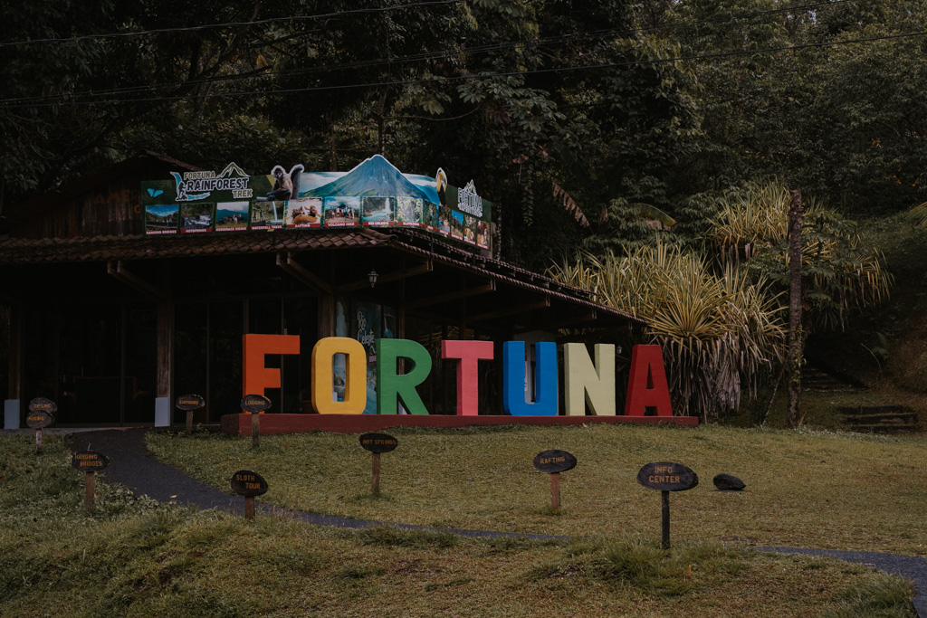 a large colourful sign reading 'Fortuna' under a wooden canopy in the rainforest