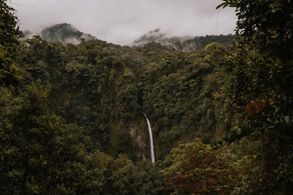 panoramic view of Arenal waterfall amongst lush rainforest with misty sky