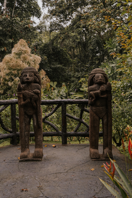 stone statues of ancient humans in the arenal hanging bridges park