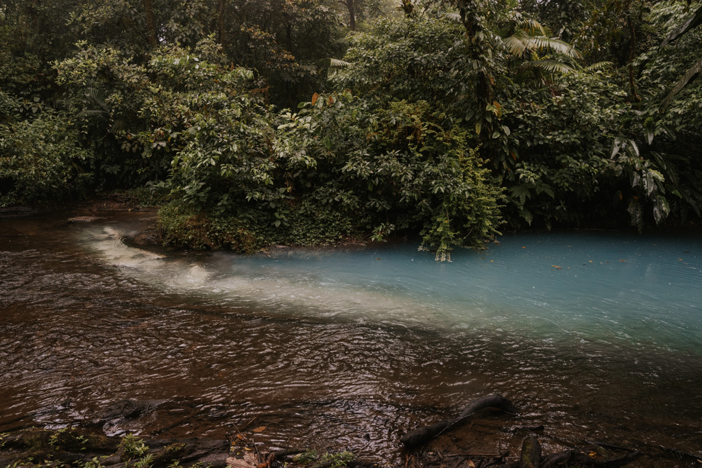 electric blue waters converge with clear water in the river of the rio celeste hike costa rica