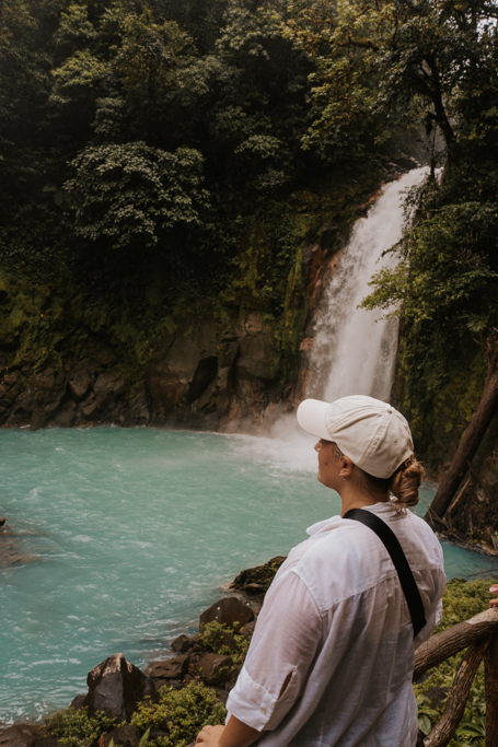 close up of a girl with white shirt and hat in front of the waterfall common on rio celeste tours