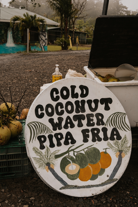a round white sign that reads 'cold coconut water pipa fria' with a picture of coconuts underneath