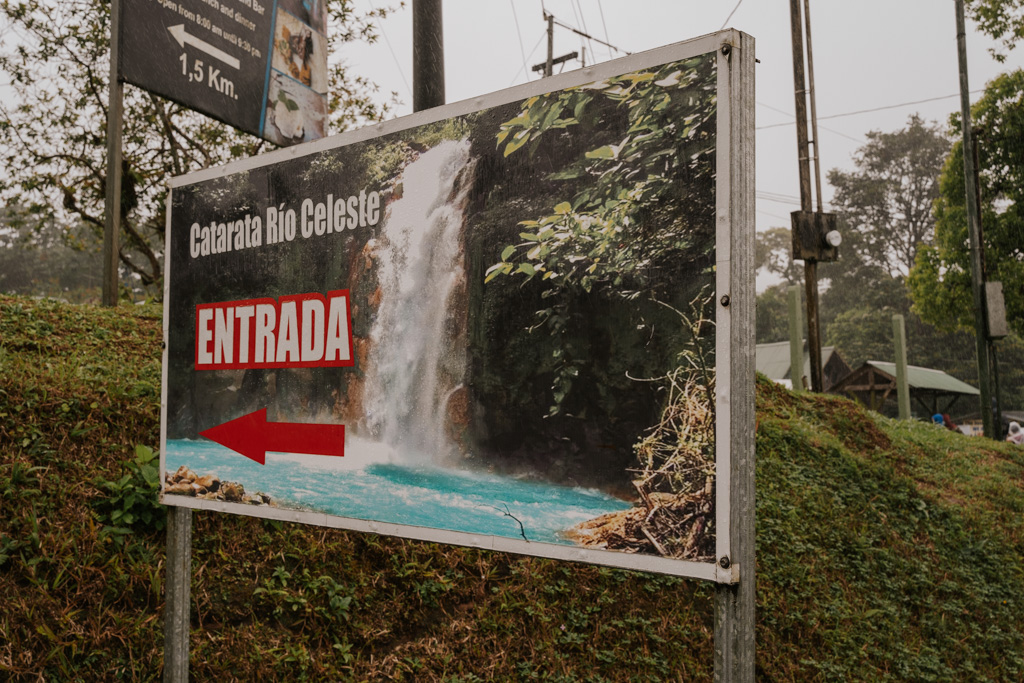 a sign that reads 'catarata rio celeste entrada' with a picture of a waterfall from la fortuna to rio celeste