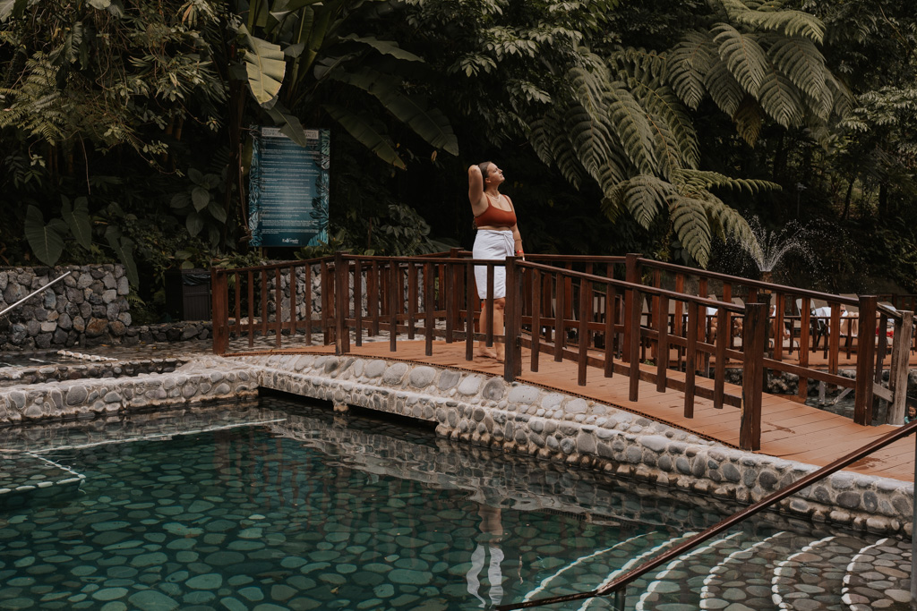 girl walking across bridge at eco termales hot springs in costa rica