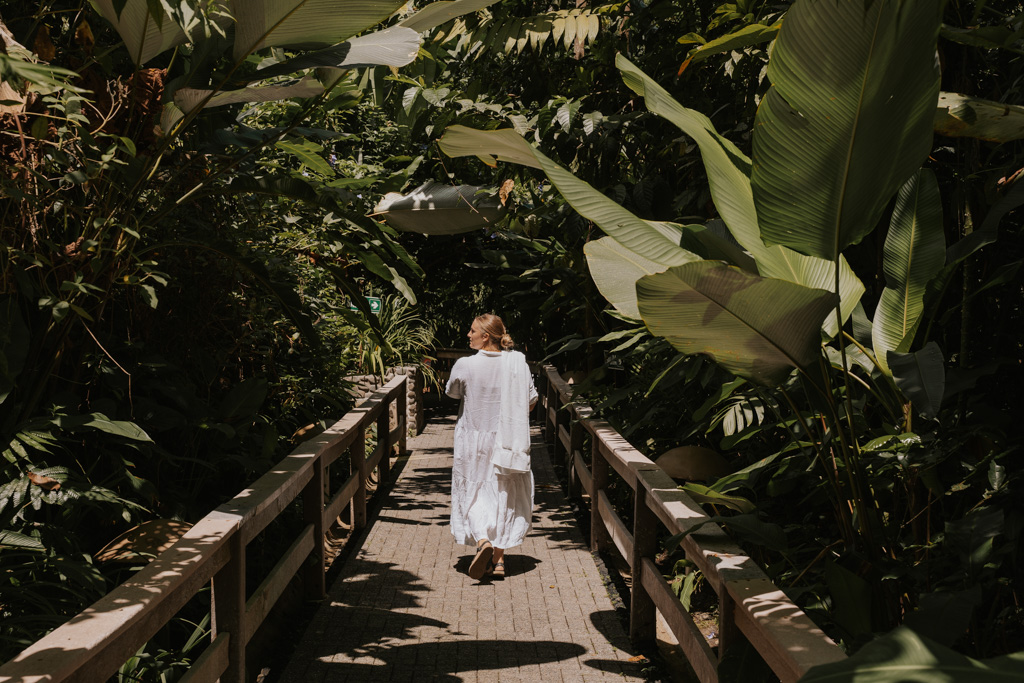girl in white dress walking along a lush pathway to eco termales costa rica hot springs