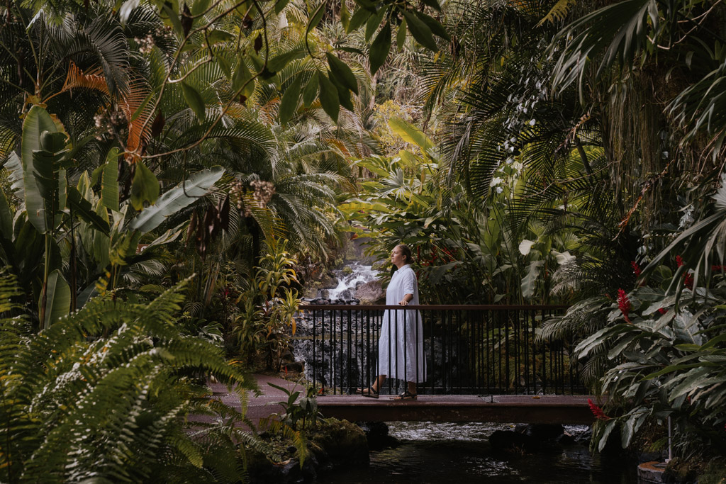 a woman in a white dress strolls across a bridge at tabacon hot spring
