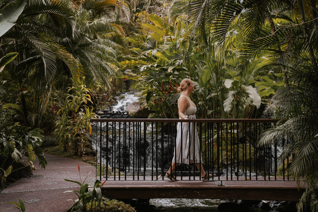 a woman walks across a bridge at the hot springs at tabacon resort costa rica