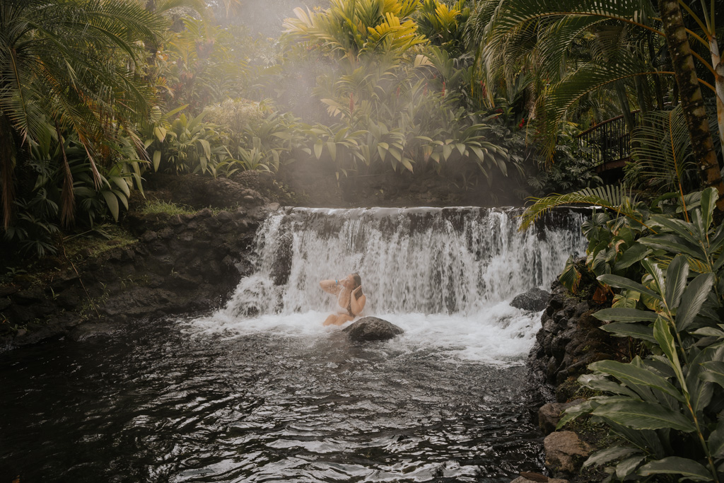 a woman sits in the springs at tabacon thermal resort spa
